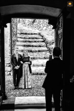 At the Chiesa di San Abbondio in Boalzo (SO), the proud groom is escorted into the historic church for the wedding ceremony, accompanied by his mother.